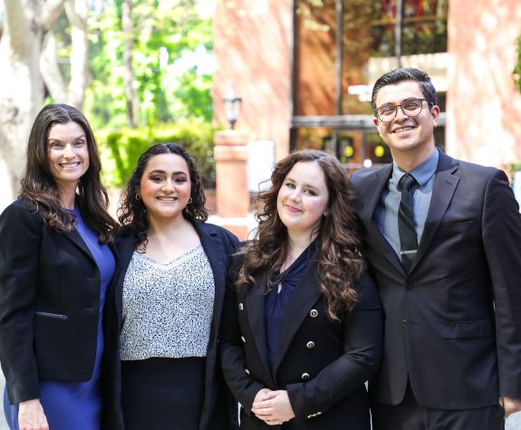 four students standing together outside